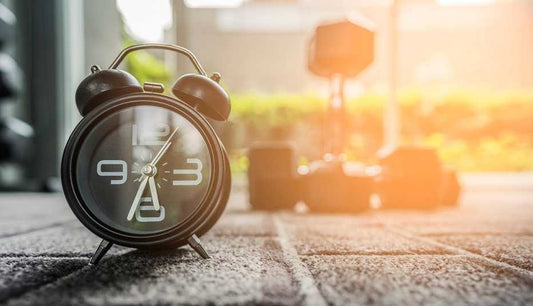 Reloj despertador sobre alfombra con luz matutina, simbolizando el mejor momento del día para tomar Pisalak y mejorar la salud digestiva