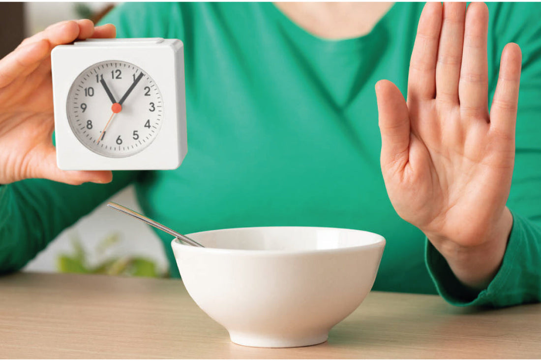 Persona mostrando un reloj y evitando comer, ilustrando la práctica de tomar suplementos como Pisalak en ayunas para favorecer la salud 